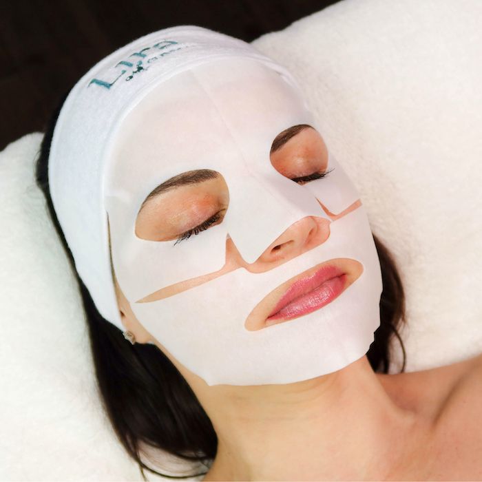 White sheet mask on woman's face, with eyes closed